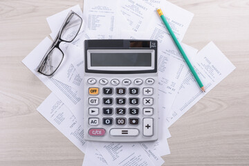 Utility bill and calculator with pencil.Financial data analyzing. expenses being calculated.Bill and saving concept.planning budget, managing expenses, finances.Top view onn woodenn background.