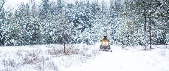Athlete rides a snowmobile in the mountains. Snowmobile in snow. Concept winter sports. A man is...