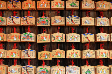 Fototapeta na wymiar Japan- February 22, 2019: Many wooden fortune amulets hanging on wall in Japanese temple or shrine at Tokyo, Japan. Pattern of object, Wood material , Faith or belief of people in Asian and Religion. 