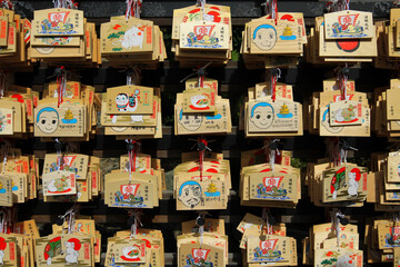 Fototapeta na wymiar Japan - February 22, 2019: Many wooden fortune amulets hanging with wish of people handwritten on wall in Japanese temple or shrine at Tokyo, Japan. Pattern of object, Faith or belief and Religion. 