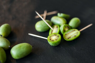 New Zealand exotic food. Berry nergi, or small kiwi. Grey stone background. Baby kiwi or mini kiwi fruits on stone background. Closeup view