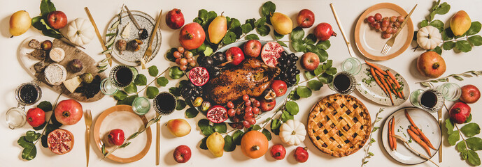 Autumn Thanksgiving, Friendsgiving or family party gathering celebration table setting. Flat-lay of Fall table with roasted duck, vegetables, cheese board, apple pie with pumpkins, fruit and leaves