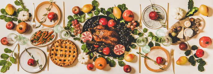 Autumn Thanksgiving, Friendsgiving, family gathering dinner table setting. Flat-lay of Fall decorated table with roasted duck in seasonal fruits, vegetables, cheese board, apple pie and wineglasses