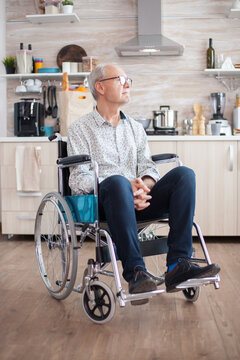handicapped senior man in wheelchair feeling lonely looking on the window. Elderly handicapped pensioner after injury and rehab, paralysis and disability for depressed invalid full of sorrow, worry