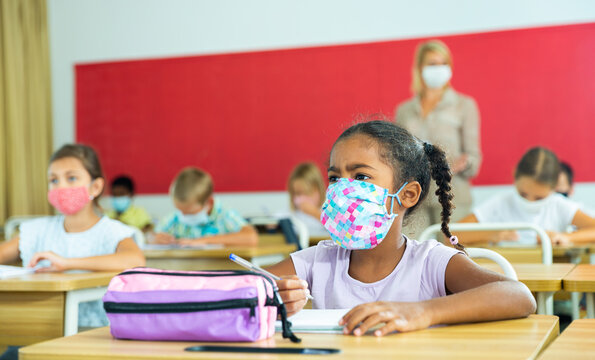 Diligent African Tween Girl In Protective Mask Studying In School With Classmates. New Life Reality In Coronavirus Pandemic