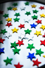 Confetti of colorful stars on the glass surface of the mirror, festive background

