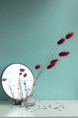 Dry lilac flowers in a transparent glass reflected in a round mirror, a modern interior