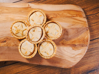 Fototapeta na wymiar Stack of mince pies on a wooden board and table. Classic Christmas pastry product