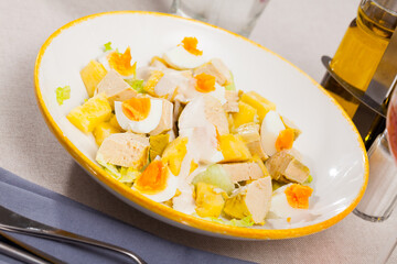 Dish with appetizing chicken salad, eggs and pineapples. High quality photo