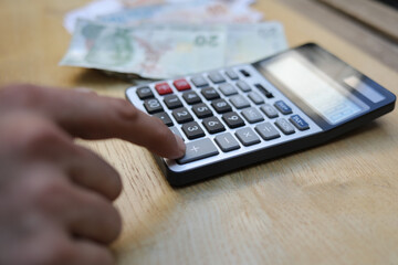man doing financial transactions with calculator holding money in hand.