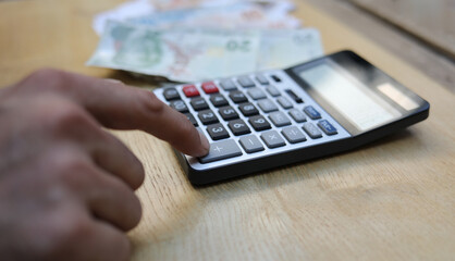 man doing financial transactions with calculator holding money in hand.