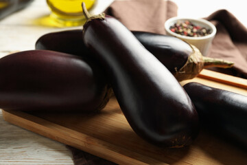 Board with eggplants and spices on white wooden background