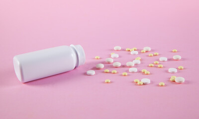 White and yellow  pills in white bottle on pink background.