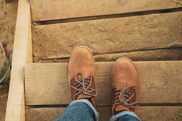 Female legs with boots on wooden steps with sand