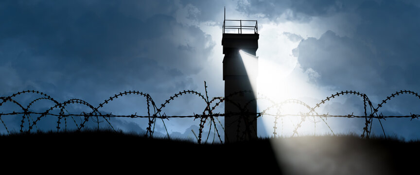 watchtower with spotlight behind barbed wire as a symbol of division