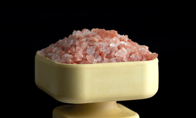 Fototapeta na wymiar Crystals of pink Himalayan salt in a salt shaker. Isolated on a black background.
