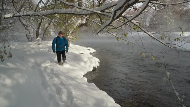 Senior make hiker is walking in a deep fresh snow along the Poudre River in Fort Collins, Colorado, foggy morning fall scenery