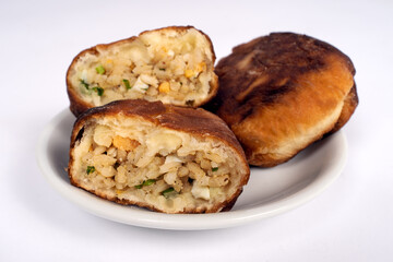 Fried homemade pies with rice, egg and herbs on little plate, white background, copy space, close up. Vegetarian food and cooking.