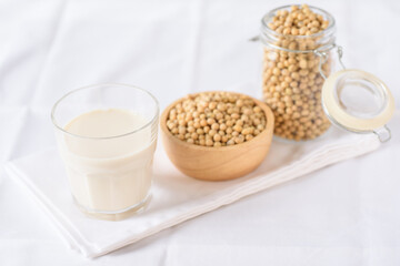 Soy milk in glass and soy bean on white background