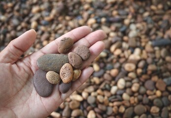 Hand hold on variety shape small pebbles stone, rough textured stone