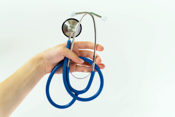 A young female doctor holds a blue stethoscope on a white background. Medical examination,...