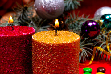 A beautiful Christmas image - a burning candle in gold color against the background of the Christmas tree. Romantic holiday photo with bokeh