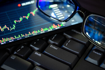 Stock market chart screen on keyboard computer and eyeglasses, online investment concept