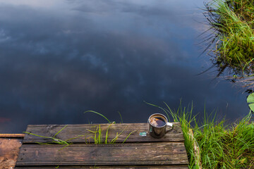 A cup of tea at the forest lake. Camping, trekking and hiking concept. Outdoor activities stock photo.