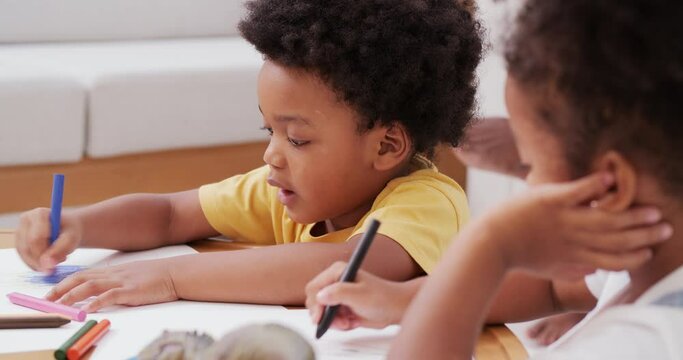 Little boy and girl drawing pictures to paper at home. They learning to draw pictures together.