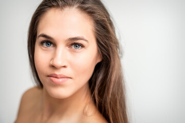 Obraz na płótnie Canvas Face portrait of young caucasian woman with natural make up and eyelash extensions looking at camera on white background