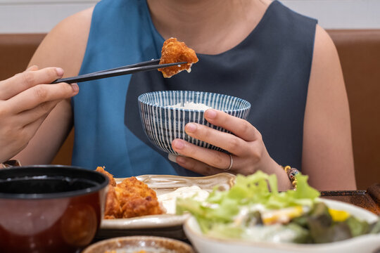 Women eating chicken fried and rice using chopsticks 
