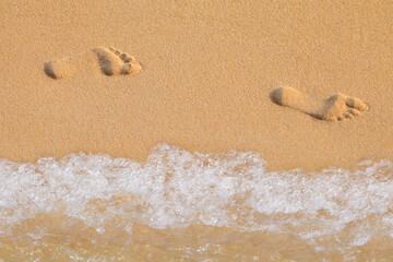 Texture background Footprints of human feet on the sand near the water on the beach