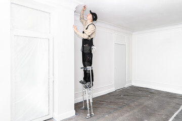 master on building stilts in a white room, glues the cells under the ceiling.