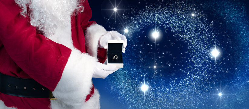 Santa is holding a jewelry case with a ring as a Christmas present in his hand