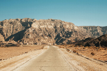 Timna National Park in Israel. Long asphalt road. Sandy desert in Israel landscape. Rocky mountain background.