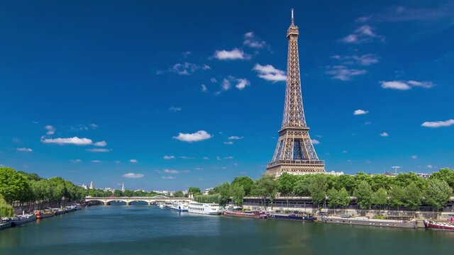The Eiffel tower timelapse hyperlapse from Bir-Hakeim bridge over the river Seine in Paris. Ship and boats on river at sunny summer day