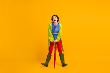 Full length photo portrait of funky laughing girl leaning on umbrella isolated on bright yellow...