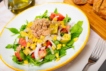 Colorful salad with canned tuna, tomatoes, avocado, onion and arugula