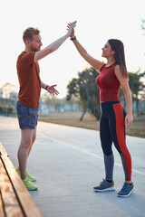 Two young sporty man and woman exercising in urban park.