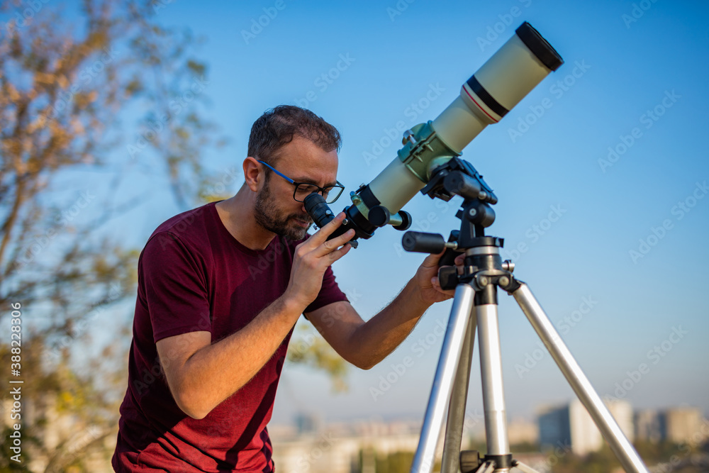 Wall mural amateur astronomer looking at the sky with a telescope.