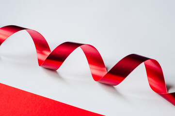 Red ribbon isolated on white. Holiday package with atlas ribbon bow. close-up
