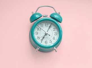 Green alarm clock on pink background.