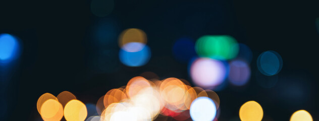 Blurred colorful bokeh light at night on dark banner background