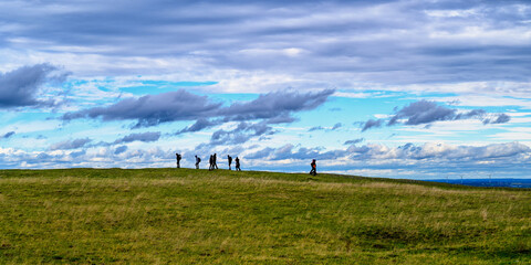 Gruppe von Wanderern am Horizont vor Wolken im Herbst auf dem Ipf am Rande des Nördlinger Ries.