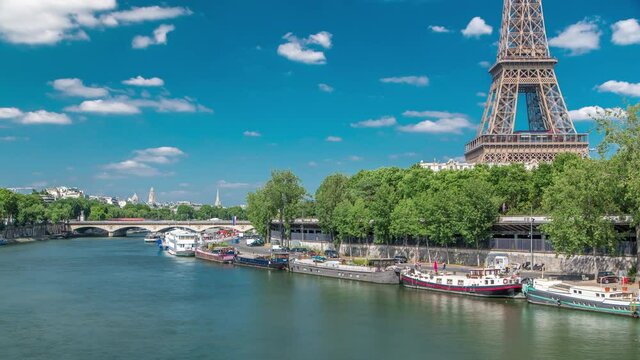 The Eiffel tower timelapse from Bir-Hakeim bridge over the river Seine in Paris. Ship and boats on river at sunny summer day