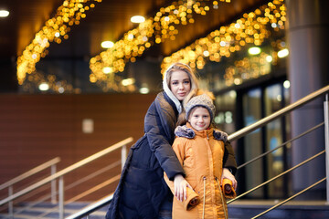 Two sisters friend outdoor in autumn winter in jackets and hats, older sister spends time together, walking around the winter city