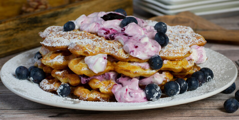 close up of a waffle cake with cream and blueberries on a plate