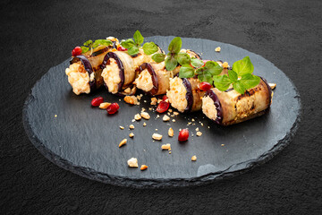 Eggplant rolls stuffed with cheese and nuts, on a stone board