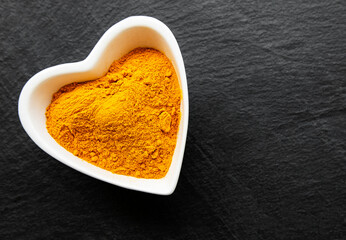 Bowl with turmeric powder  on a black concrete background