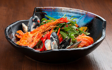 Seafood salad: shrimp, mussels and salmon, arugula and oranges. In a decorative plate
